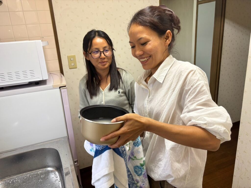 四国の社宅キッチンで外国人介護スタッフが炊飯器の準備をする定着支援・生活サポートの様子